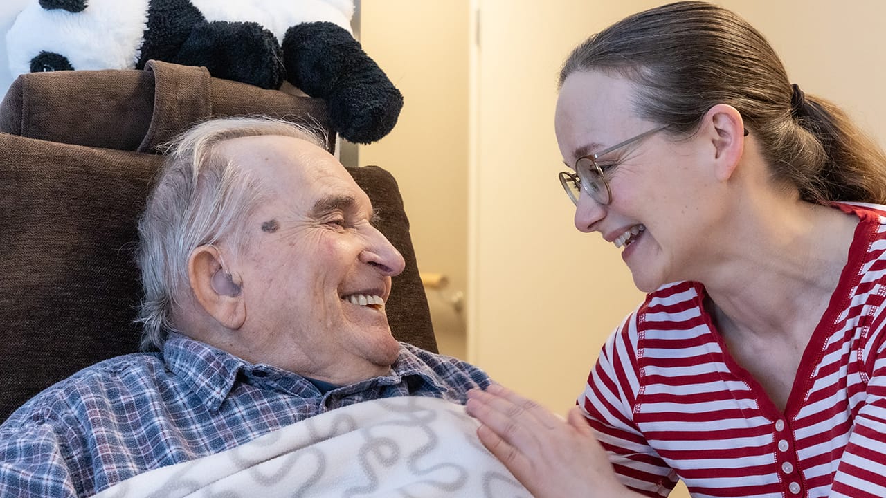Esperi Hoivakoti Lauttalammen asukas ja hoitaja hymyilevät toisilleen