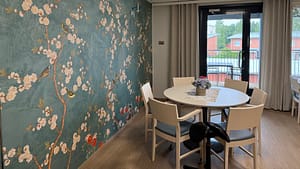 Esperi Hoivakoti Lehtokertun oleskelutila, jossa on pyöreä pöytä ja näyttävä kukkatapetti.