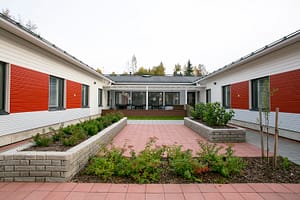 Talon julkisivu, jossa talon edessä on kukkapenkkejä.