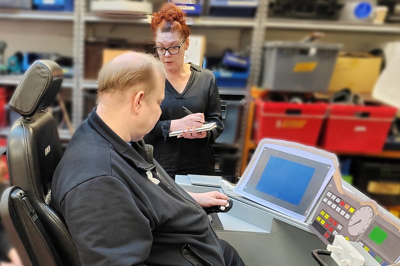 LINKin ergonomia-asiantuntija ja asiakkaan käyttäjätestaaja tutkivat ohjaamoergonomian toimivuutta 1:1 kokoisen ohjaamon mock-upin avulla
