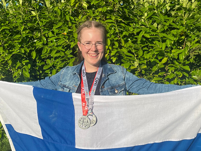 Aino Aulanko voitti matematiikan olympialaisissa ja levittää Suomen lippua.